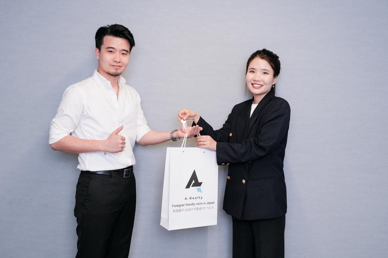 Happy client receiving a branded A-Realty welcome bag from a team member